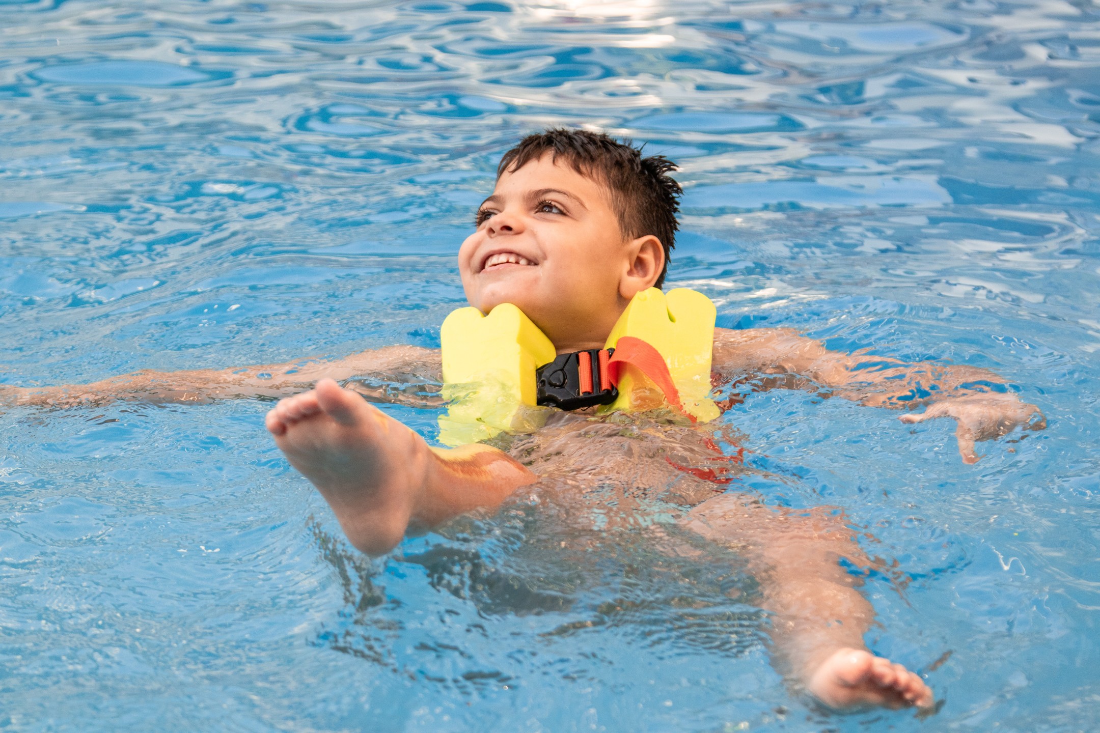 A child with a disability is learning to swim as part of their physiotherapy sessions.